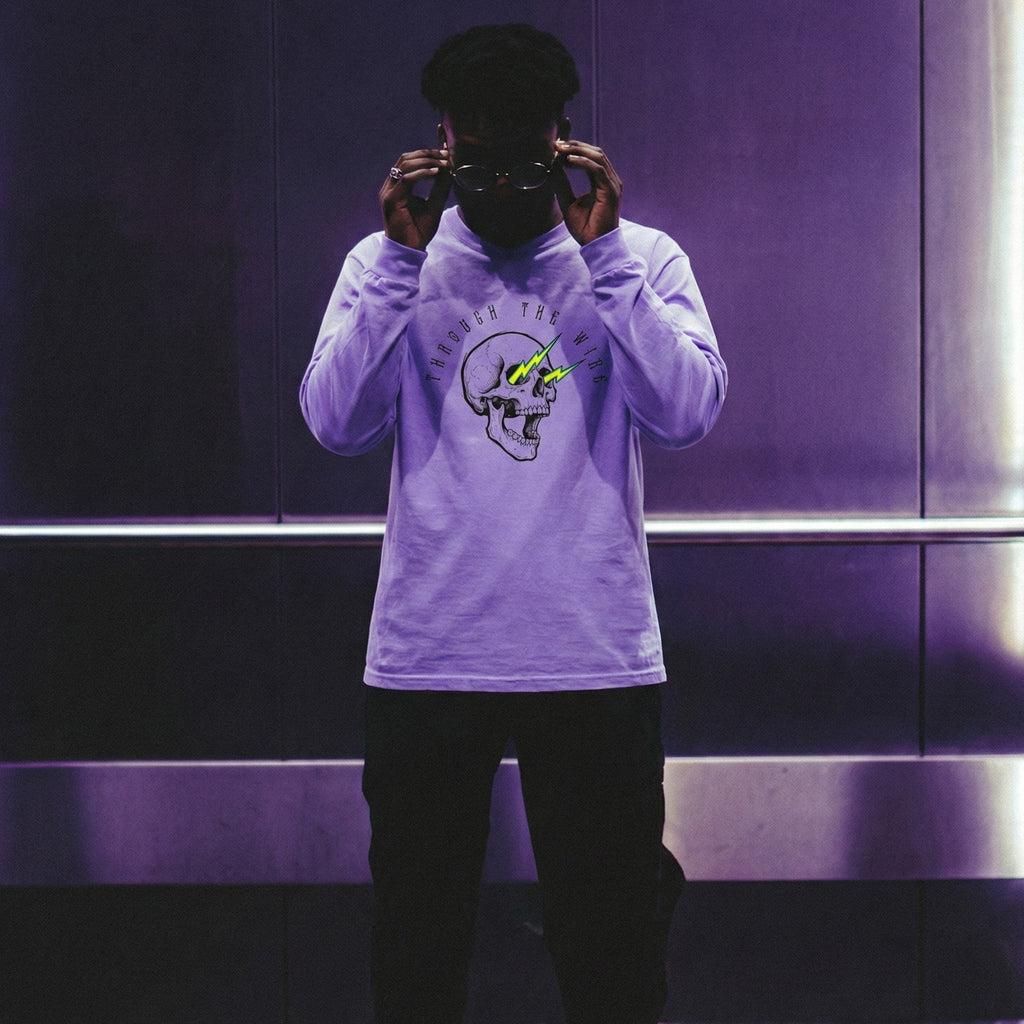 Person wearing a light purple sweatshirt with a graphic design, black pants, and green sneakers in a reflective surface setting.